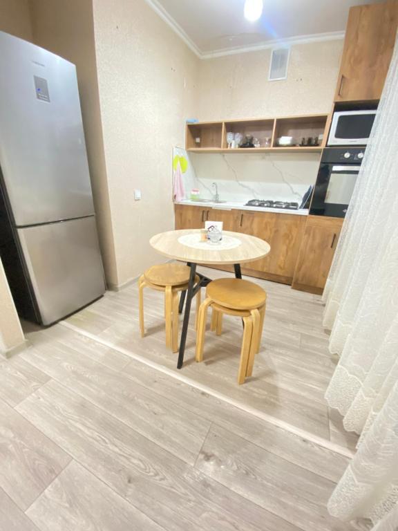 a kitchen with a table and two chairs and a refrigerator at 2кмн Квартира по проспекту Республики 8 in Astana