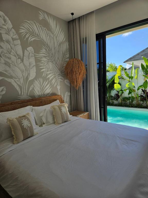 a bedroom with a bed and a large window at White Shell Villas in Uluwatu