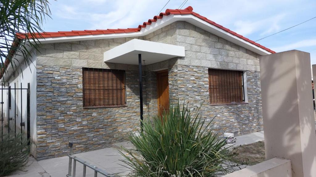 a small brick house with an umbrella in front of it at Casa a 800 mts de pleno centro in Villa Carlos Paz