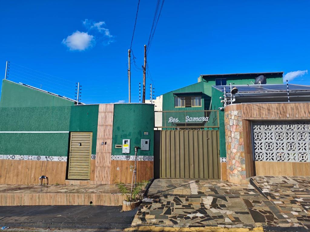 a green building with a gate and a fence at Residencial Samara in Rondonópolis