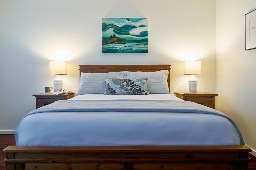 a bedroom with a large bed with two lamps at Liahona Guest House in Ucluelet