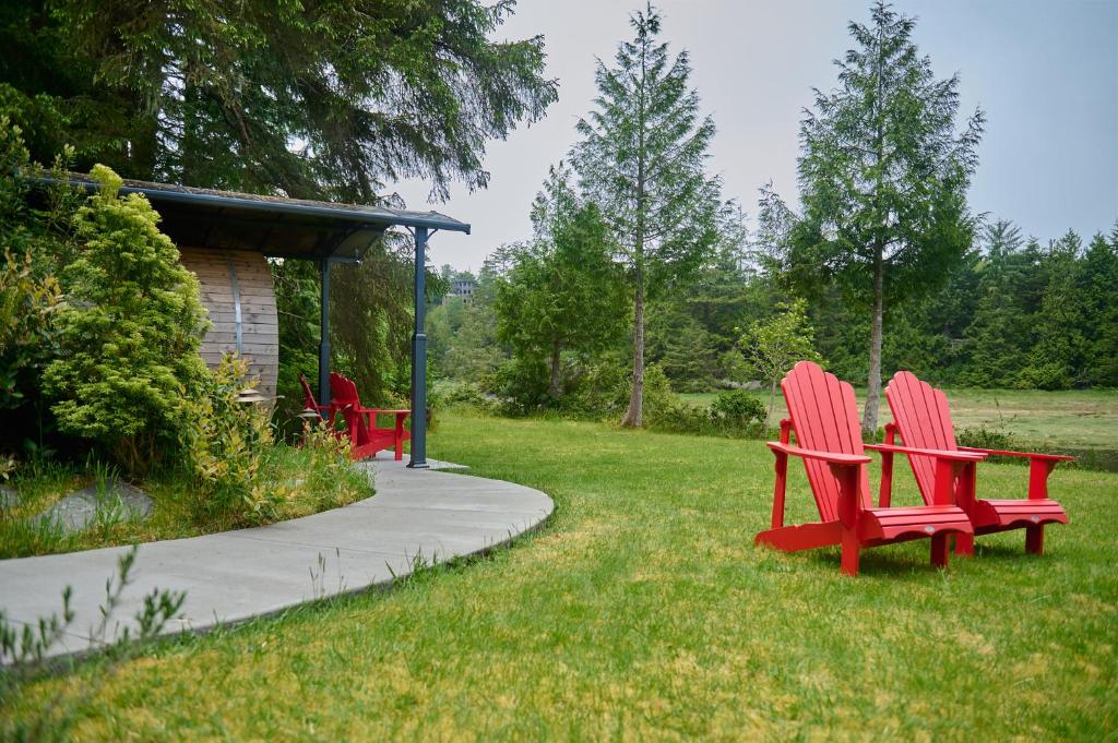 two red chairs sitting in the grass near a gazebo at Liahona Guest House in Ucluelet