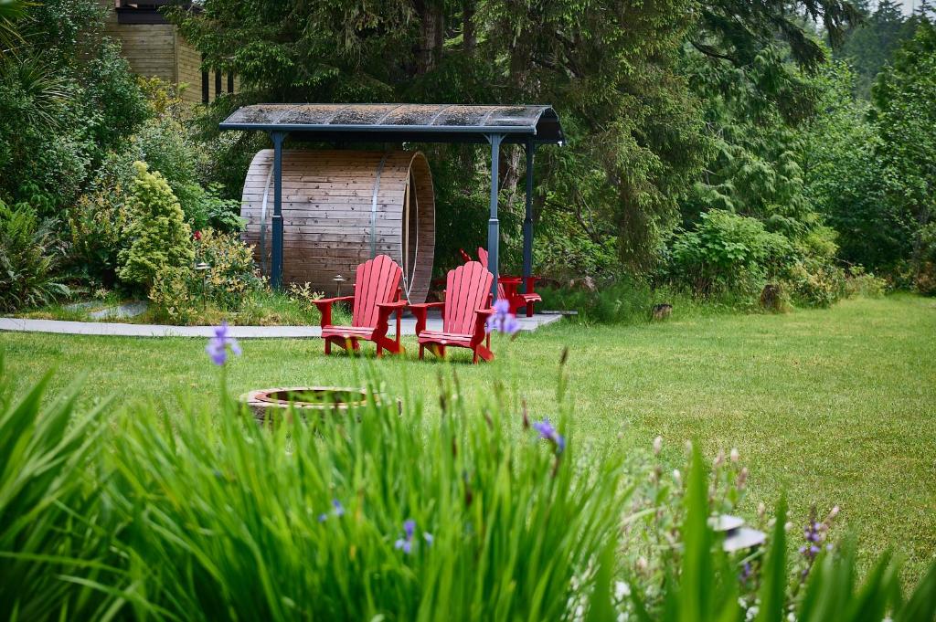 two red chairs and a table in a yard at Liahona Guest House in Ucluelet