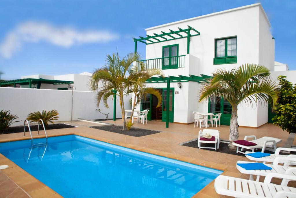 a villa with a swimming pool in front of a house at Villas Costa Papagayo in Playa Blanca