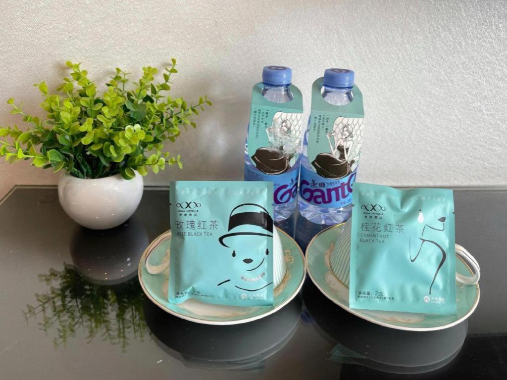 two bottles of water on a table with plates and a plant at Xana Hotelle Xiamen Airport Zone Government in Xiamen