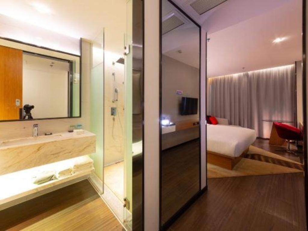 1 dormitorio con 1 cama y baño con lavamanos en Borrman Hotel Zhanjiang Xuwen Port Terminal, en Xuwen