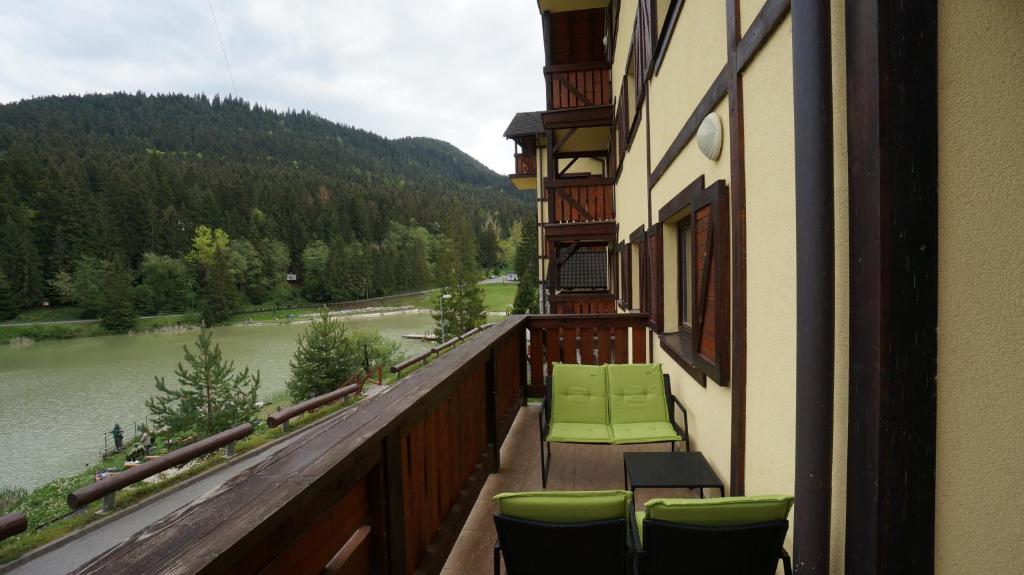 einen Balkon mit grünen Stühlen und Flussblick in der Unterkunft Vila Olympia - Apartmán Olympia 3 in Ružomberok