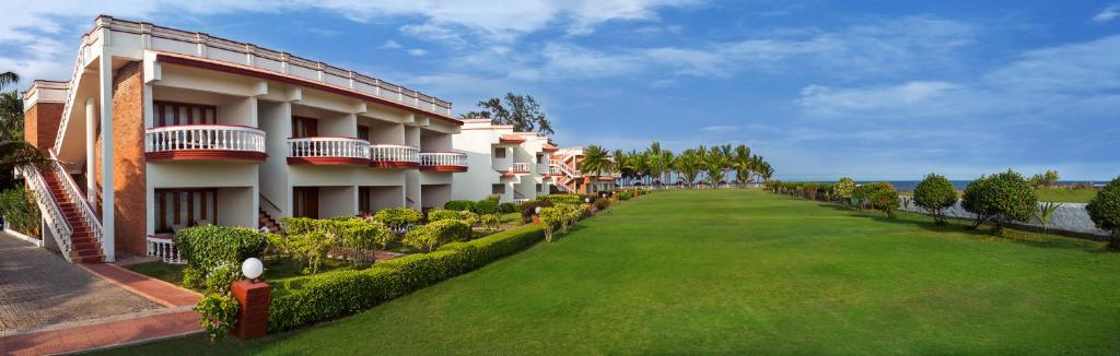 a building with a green lawn in front of it at Ideal Beach Resort in Mahabalipuram