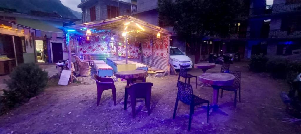 Un grupo de mesas y sillas en un patio por la noche. en The North-East Breeze, en Jāmb