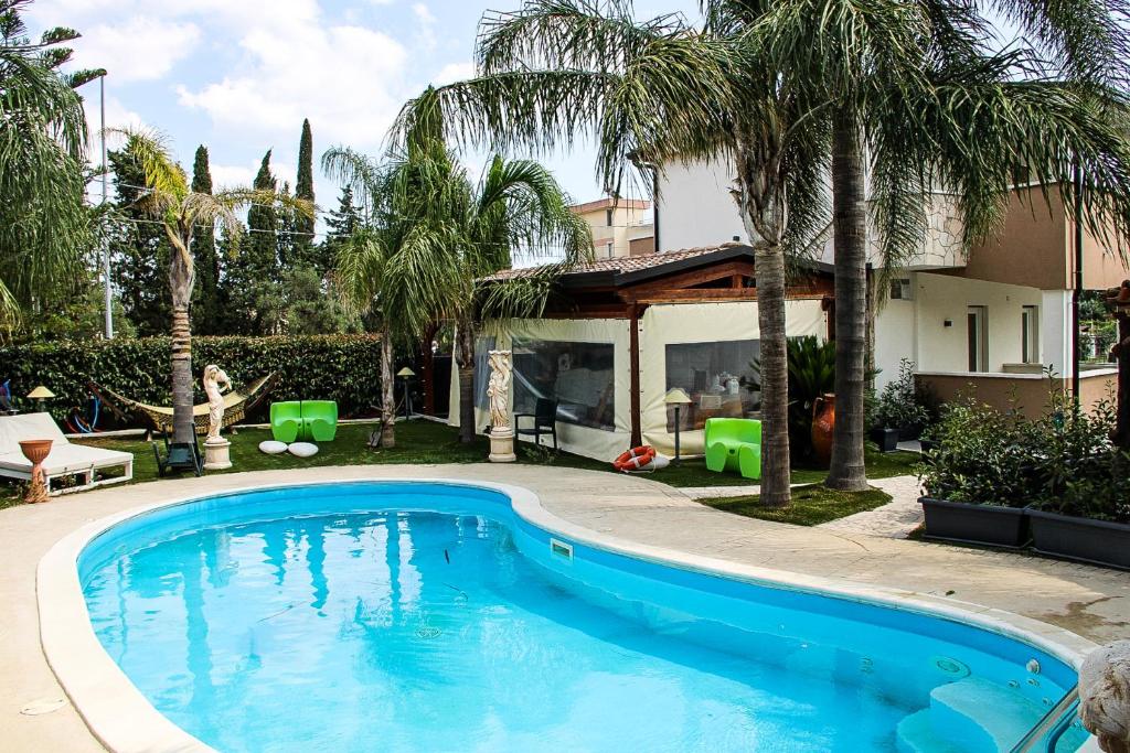 a swimming pool in front of a house with palm trees at Villa Rosanna in Ginosa Marina