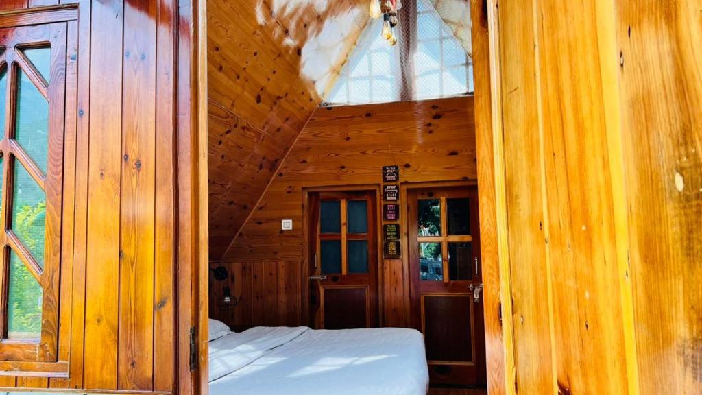 una camera da letto in una cabina di legno con un letto in esso di A Shape River Side Cabin a Jāmb