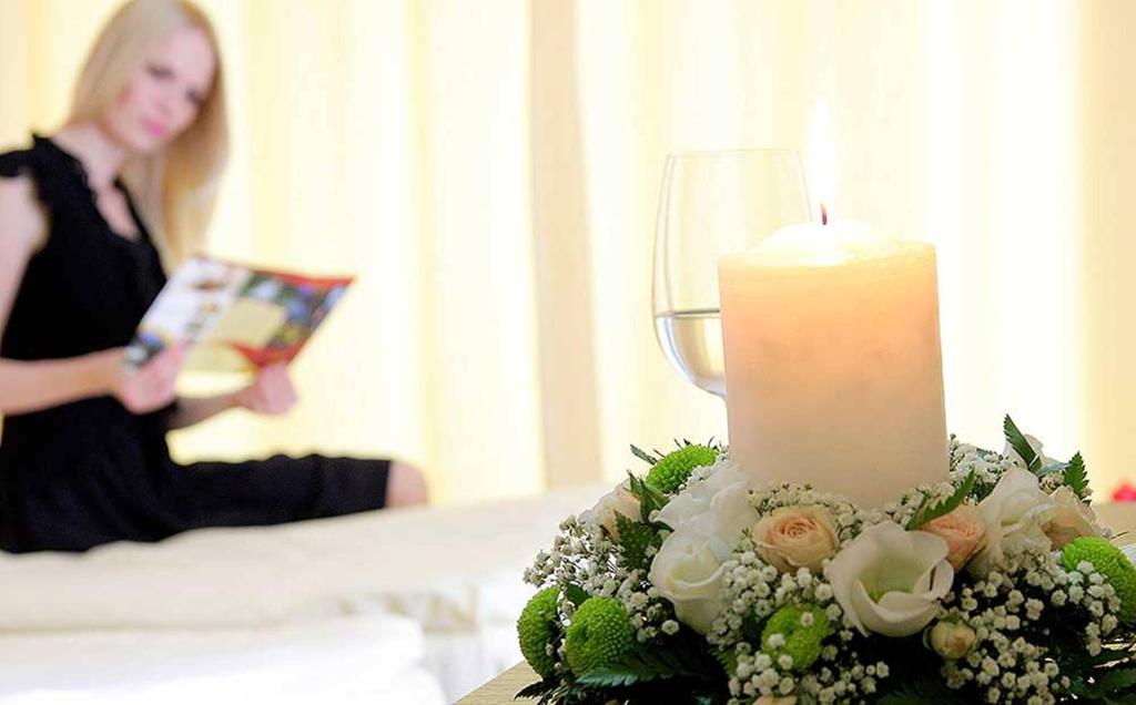a woman in a room with a candle and flowers at Hotel Royal Spa in Banja Koviljača