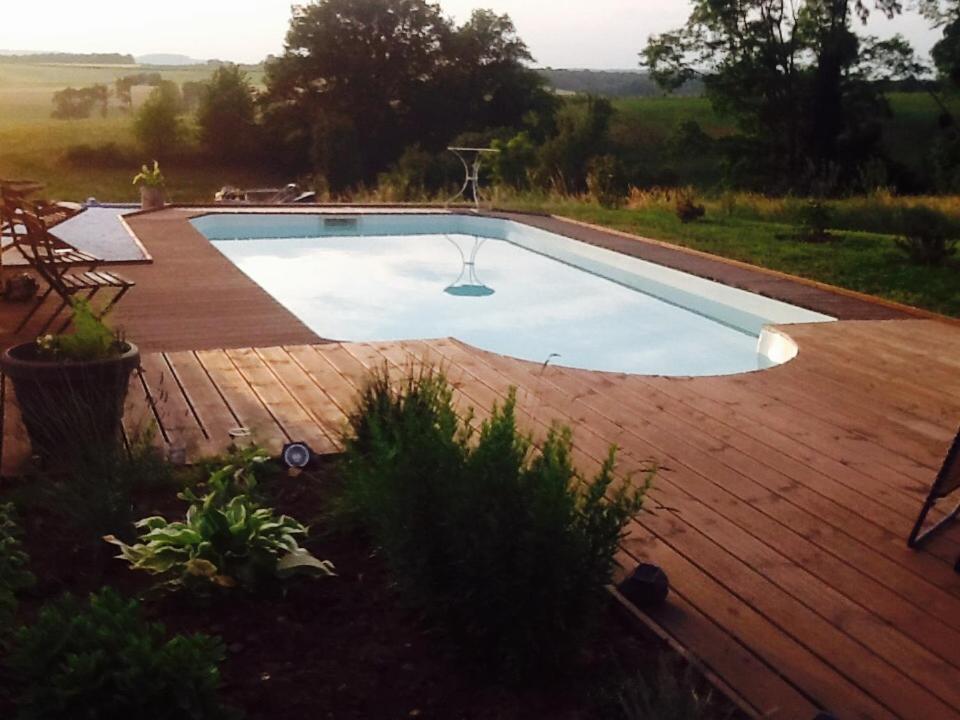 uma piscina com um deque de madeira em La Maison de Jeanne em Châteney