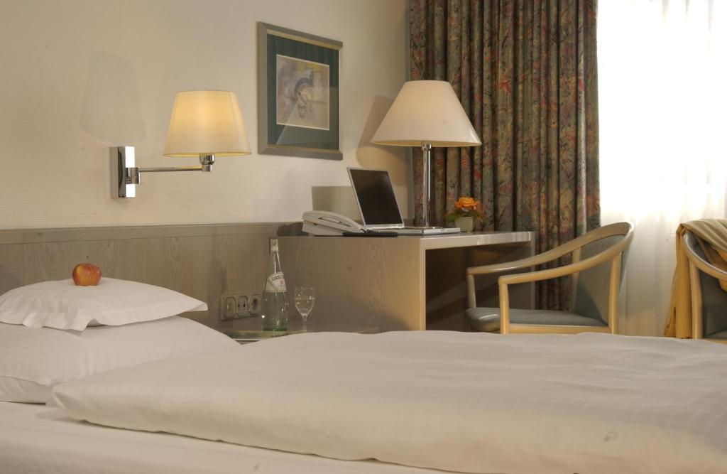 a hotel room with a bed and a desk with a laptop at Hotel Spiegel in Cologne