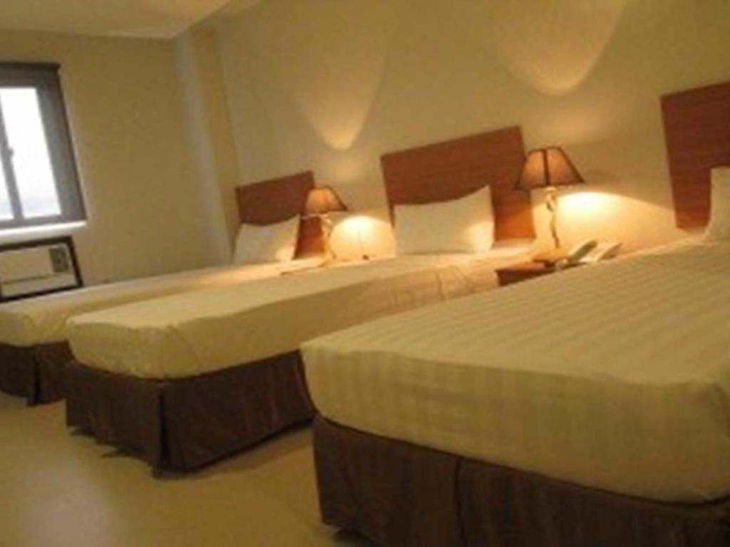 a hotel room with two beds and a window at Mango Suites - Isabela in Santiago City