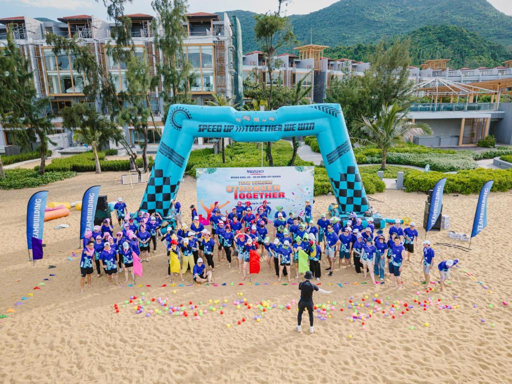 un gruppo di bambini in piedi davanti a un arco sulla spiaggia di Angsana Lang Co a Lăng Cô