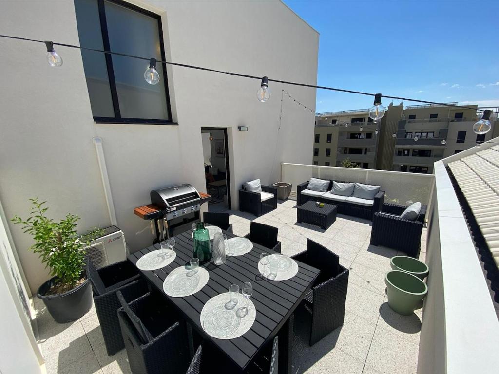 un patio avec une table et des chaises sur un balcon dans l'établissement Skyview 360 - Rooftop - 3 Terrasses - Parking - Climatisation, à Saint-Jean-de-Védas