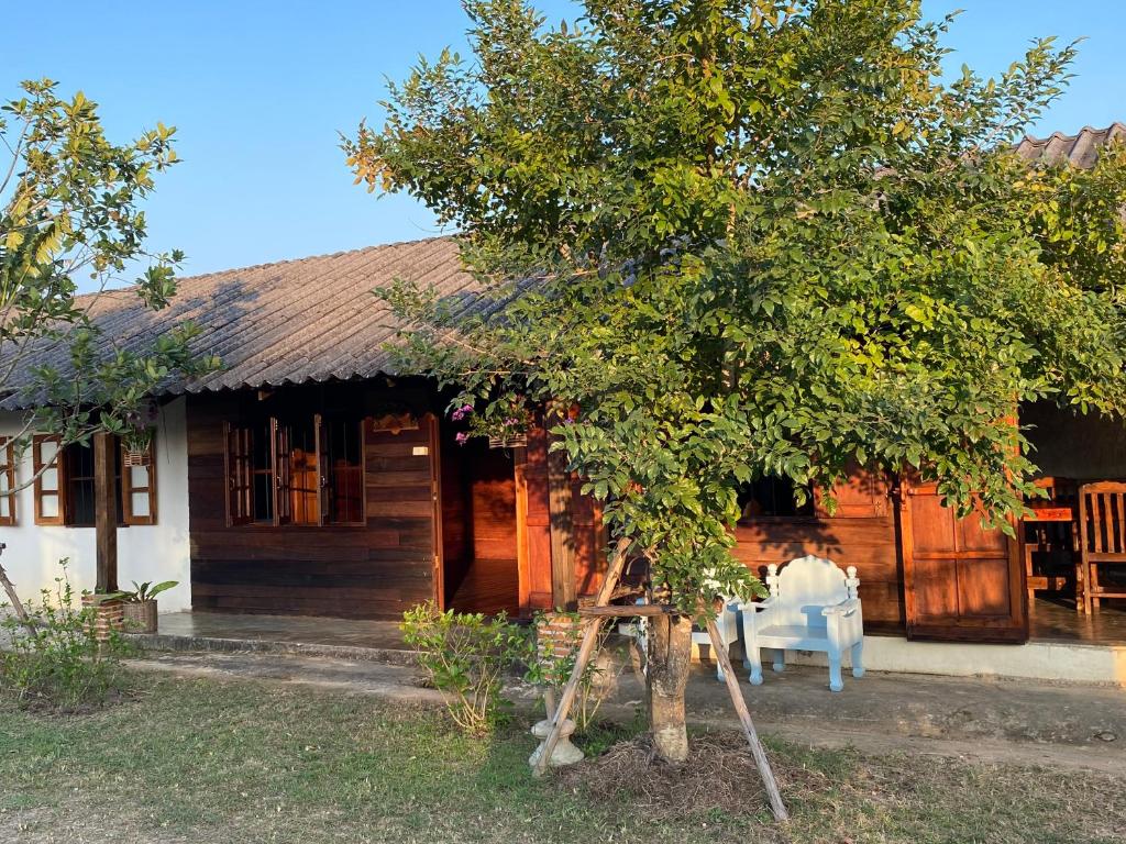 a wooden house with a table and a tree at Baan Khoyee Boutique บ้านโกยีบูทีค 