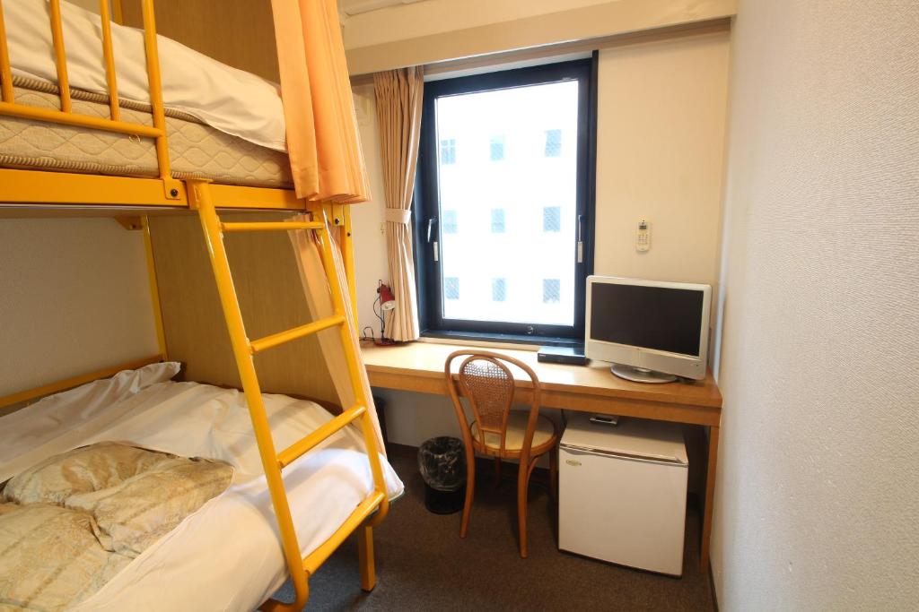 a bedroom with a desk with a computer and bunk beds at Sakura Hotel Ikebukuro in Tokyo