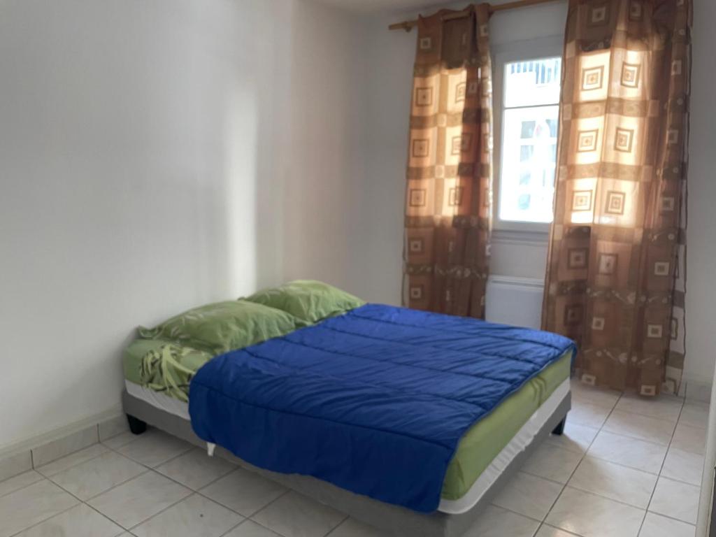 une chambre avec un lit avec des draps bleus et une fenêtre dans l'établissement Au soleil, à Toulon