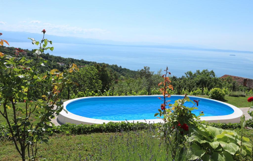 a swimming pool in a garden with a view of the ocean at Beautiful Casa Dea with pool in Opatija in Ičići