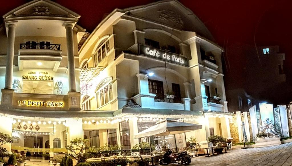 un grand bâtiment avec un restaurant devant lui la nuit dans l'établissement Le Petit Paris Dalat Hotel, à Đà Lạt