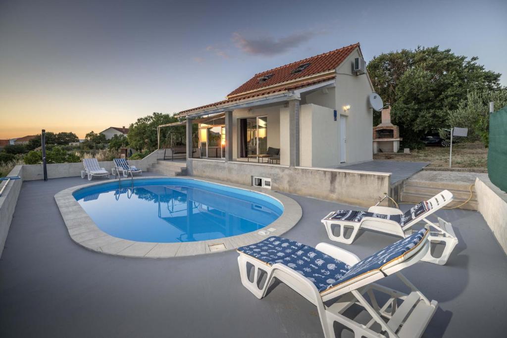 una piscina con due sedie a sdraio e una casa di Villa Baras garden - house with pool a Mirce