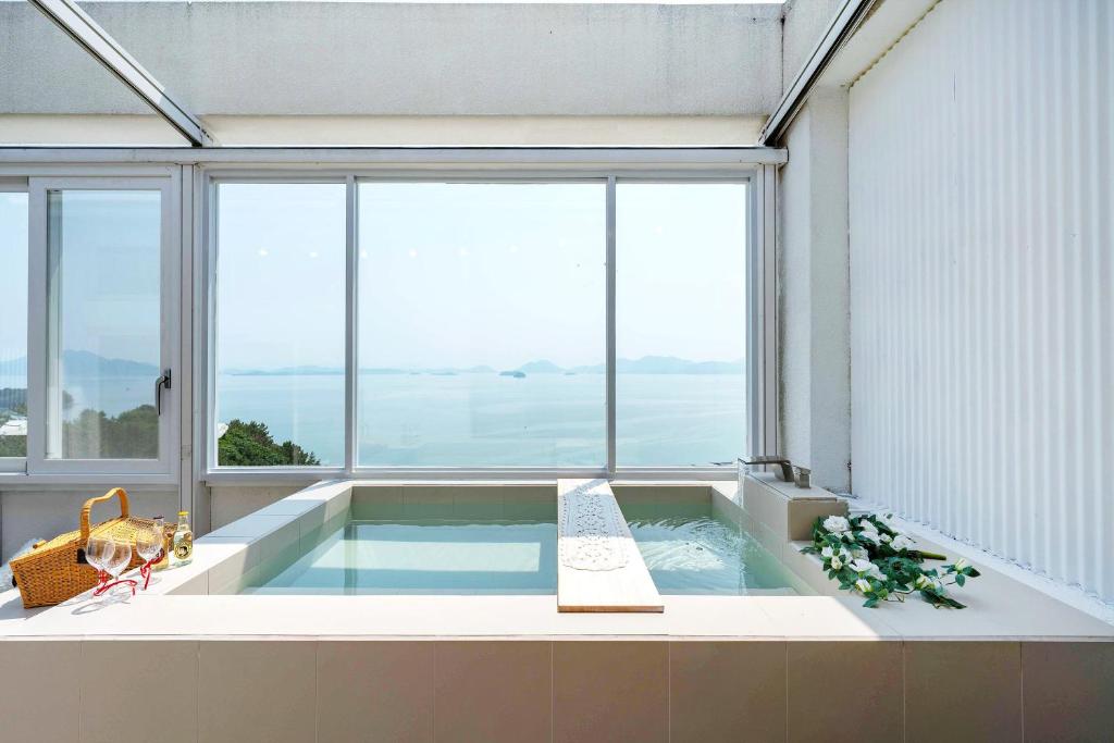 a hot tub in a room with a large window at Yeosu Ekklesia Pool Villa N Jacuzzi in Yeosu