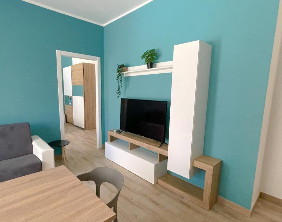 a living room with a flat screen tv on a blue wall at LA RIVA DEL '44 Apartments - Elegant, spacious, and bright holiday homes just a few steps from Nettuno's finest beach in Nettuno