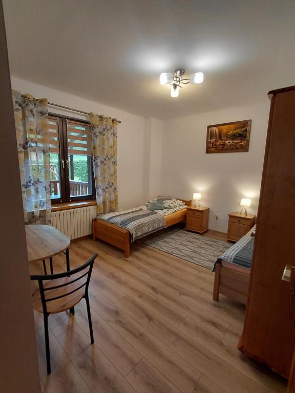 sypialnia z dwoma łóżkami, stołem i oknem w obiekcie Apartament Na Rozdrożu w Cisnej