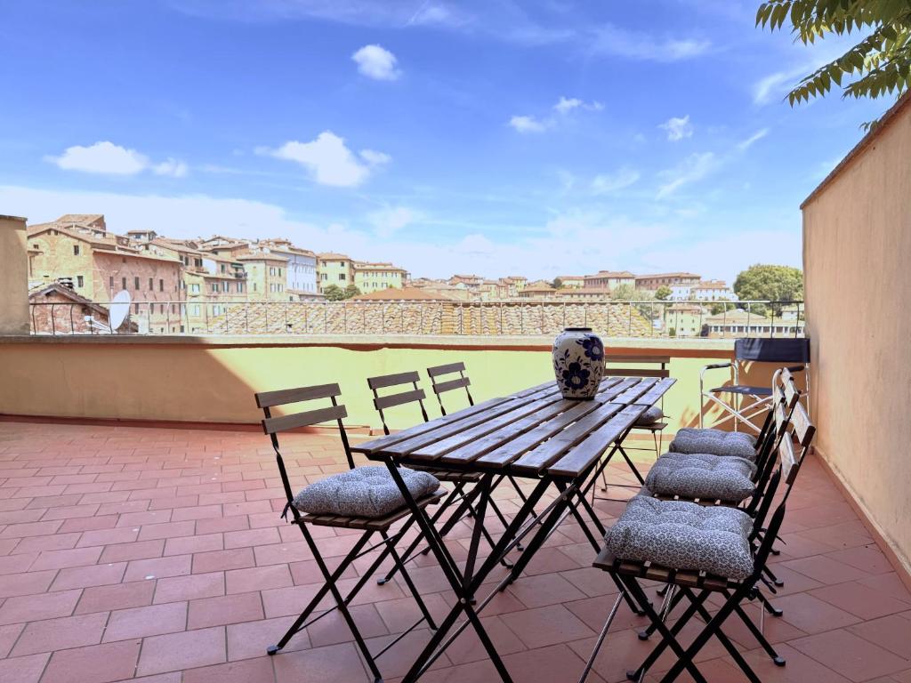 een houten tafel en stoelen op een terras bij Abbadia Panoramic Terrace in Siena