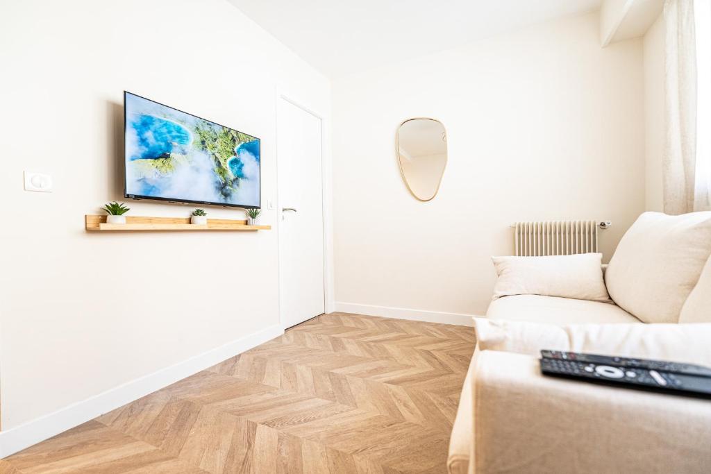 un salon avec un canapé et une télévision sur un mur dans l'établissement L'Escale Niçoise, à Nice