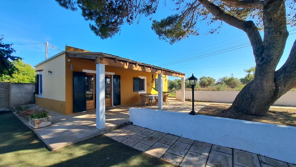 a small yellow and white house with a tree at Cas Conco in Ciutadella