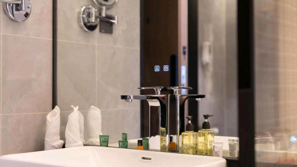 a bathroom sink with a large mirror and a sink at 沃德酒店济南经十东路融创文旅城店 in Jinan