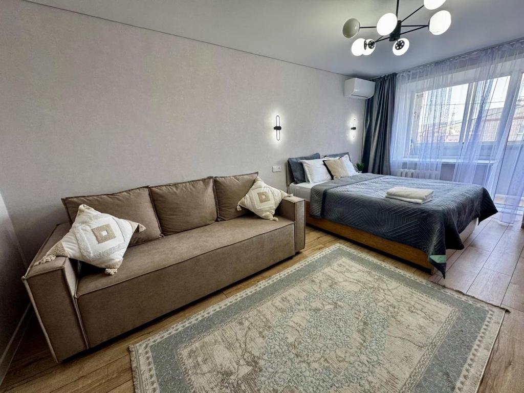 a living room with a couch and a bed at Квартира с видом на город in Ustʼ-Kamenogorsk