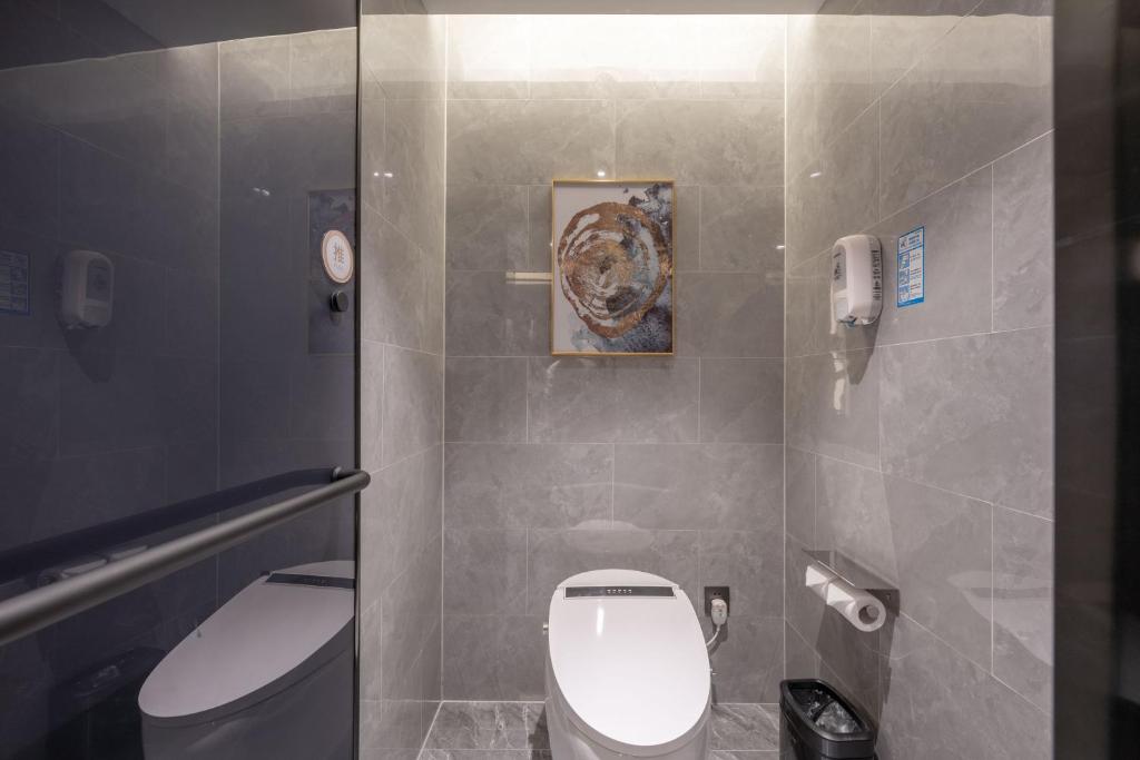 a bathroom with a toilet and a picture on the wall at 沃德酒店济南经十东路融创文旅城店 in Jinan