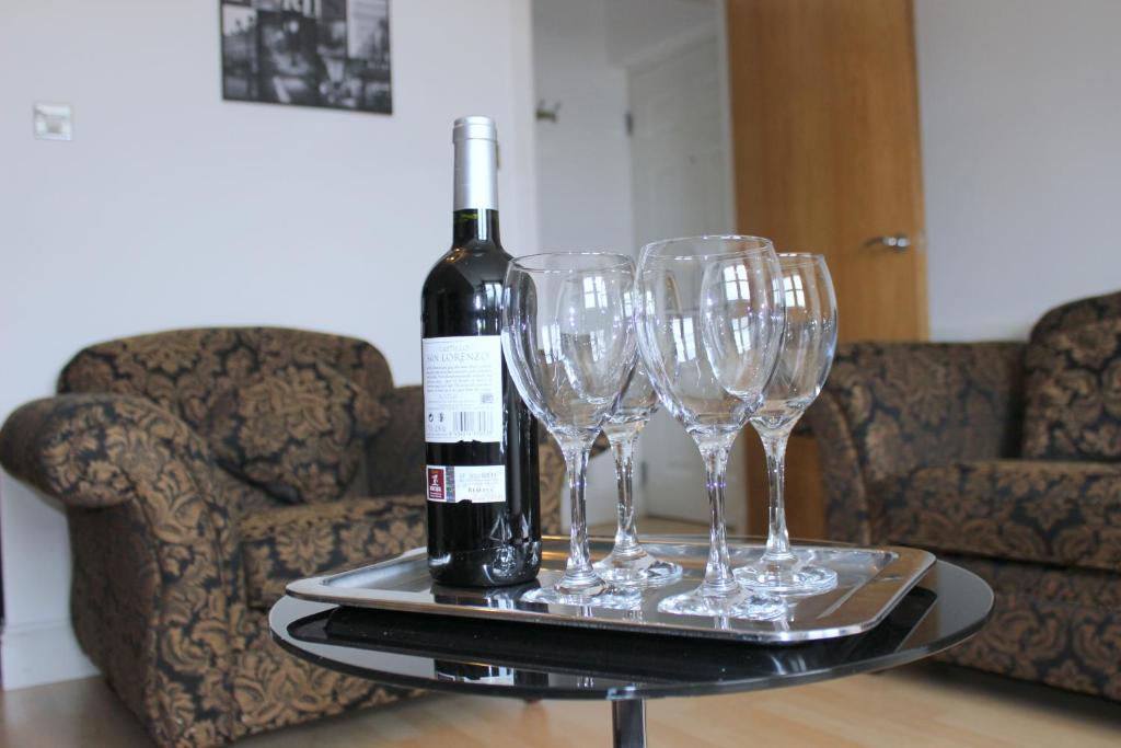a tray with a bottle of wine and four wine glasses at Bego's Apartment in Aberdeen
