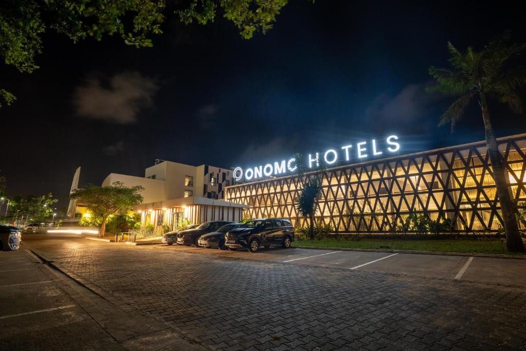 a building with cars parked in a parking lot at night at ONOMO Hotel Abidjan in Abidjan