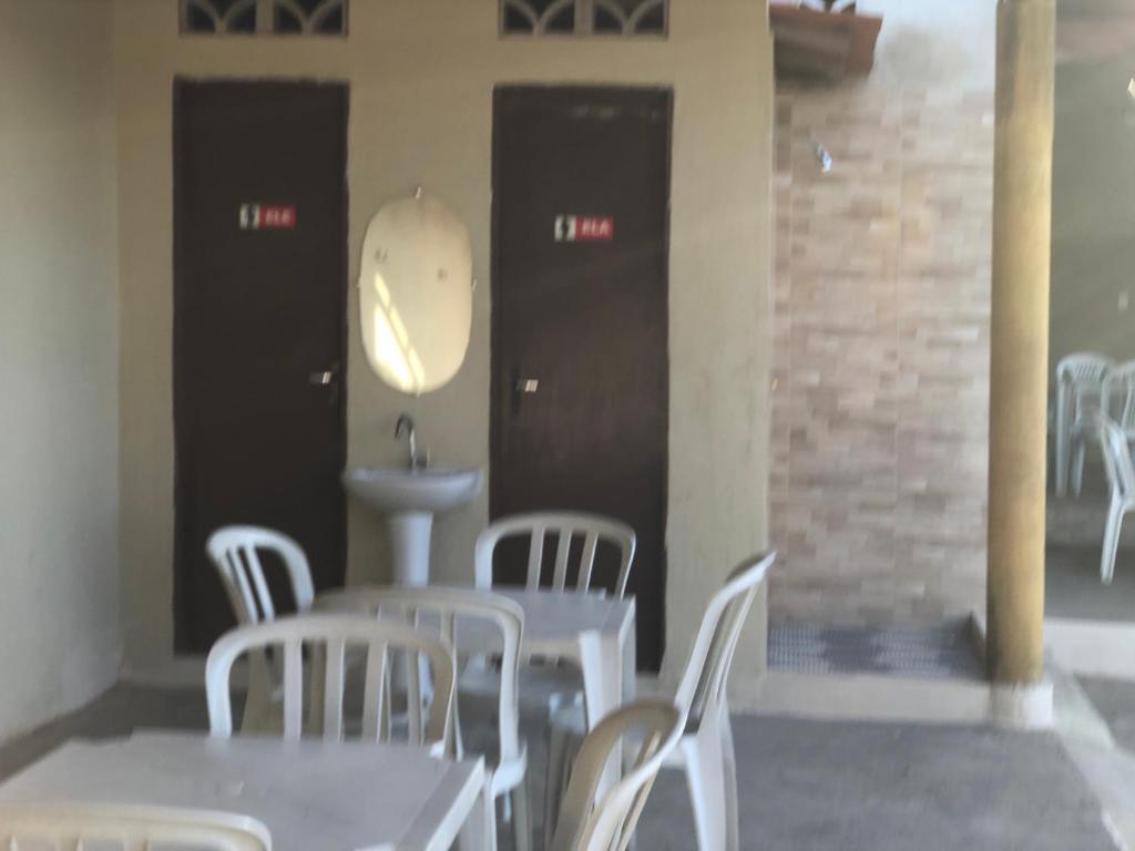 een kamer met tafels en witte stoelen en een wastafel bij Chácara GLclube 