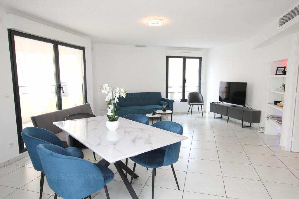 - un salon avec une table blanche et des chaises bleues dans l'établissement Paradisio, à Cannes