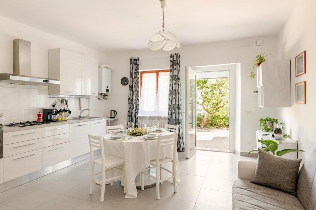 a white kitchen with a white table and chairs at I Due Gelsi Appartamento White in Monte San Giusto