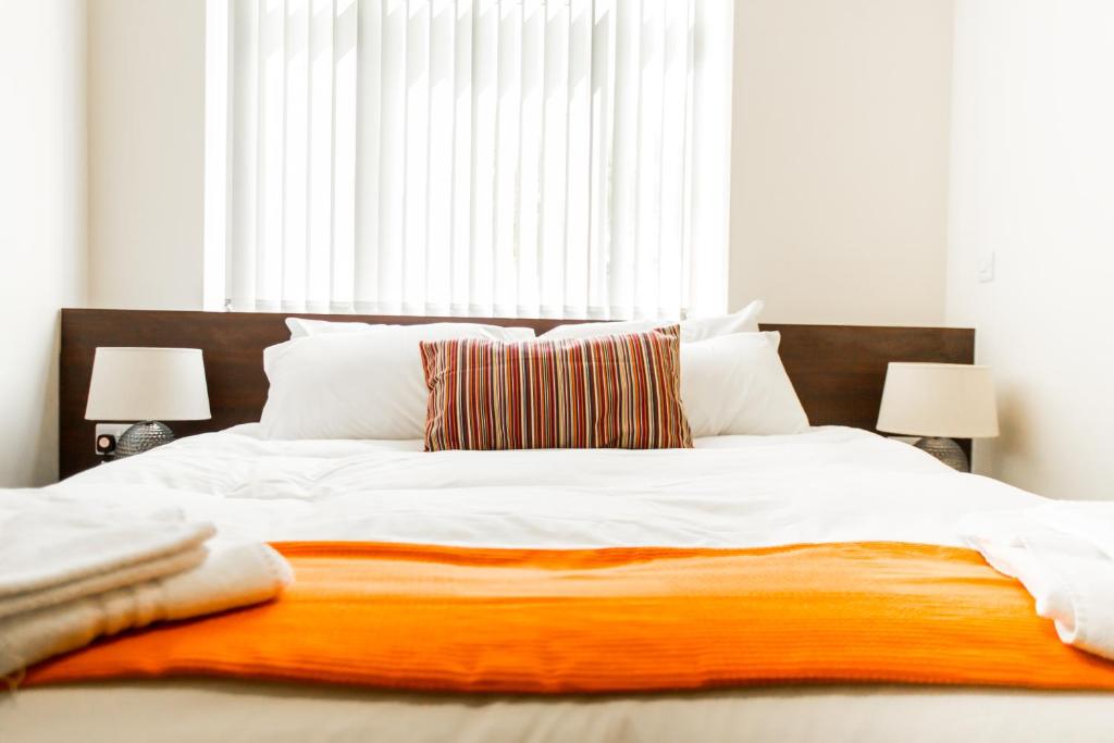 een slaapkamer met een groot bed en een oranje deken bij Whiteley Mill in Stapleford