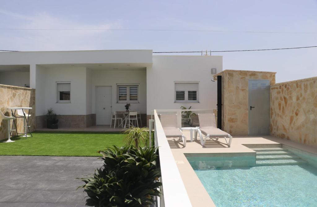 a patio with two chairs and a swimming pool at Casa el rincon de la Rosa II in Conil de la Frontera