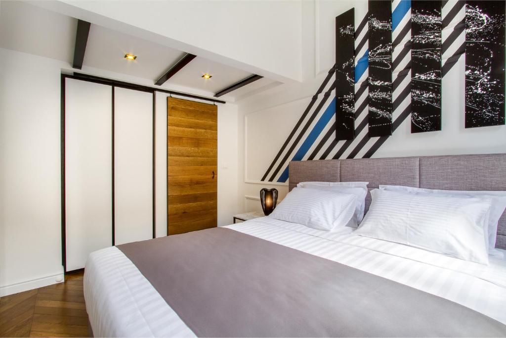 a bedroom with a large bed with white sheets at DeZign Superior Apartments & Rooms in Zadar