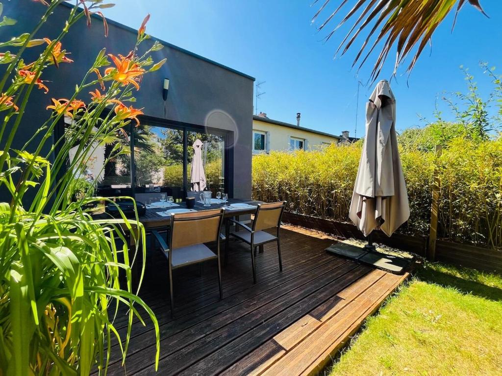 une terrasse en bois avec une table et un parasol dans l'établissement Casa Belfort - T3, à Angers