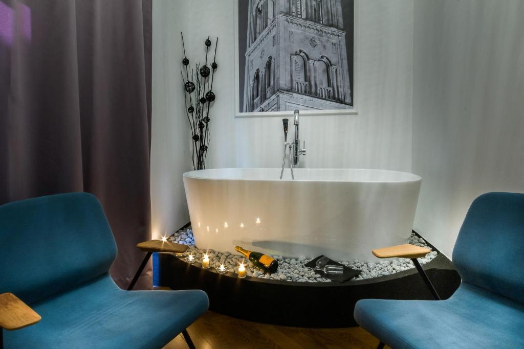a bath tub in a room with two blue chairs at DeZign Superior Apartments & Rooms in Zadar
