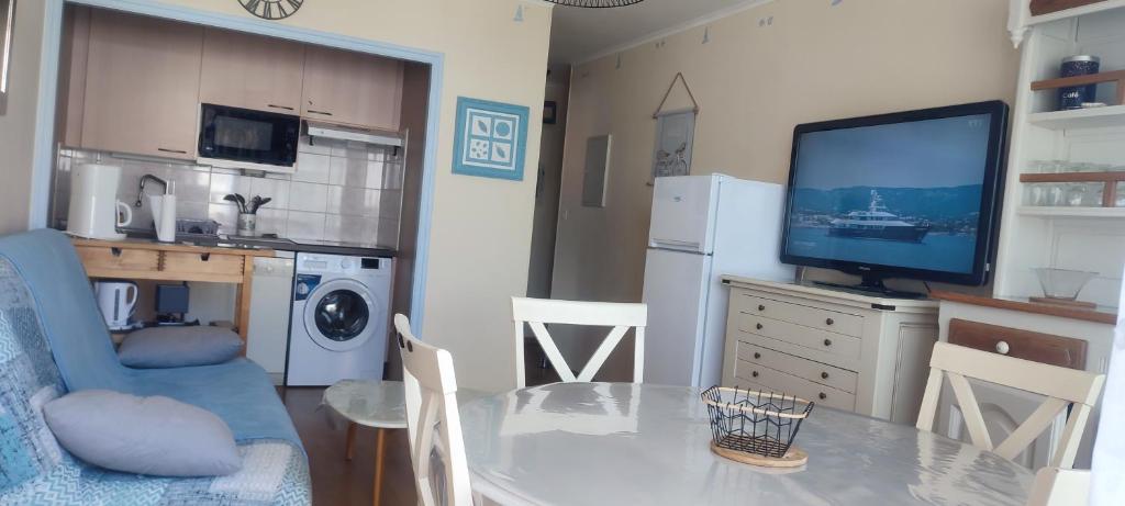 Il comprend une petite cuisine avec une table à manger et une télévision. dans l'établissement Appartement T2 450m de la plage des demoiselles, avec garage et possibilité de vélos à 950m de la rue piétonne, à Saint-Hilaire-de-Riez
