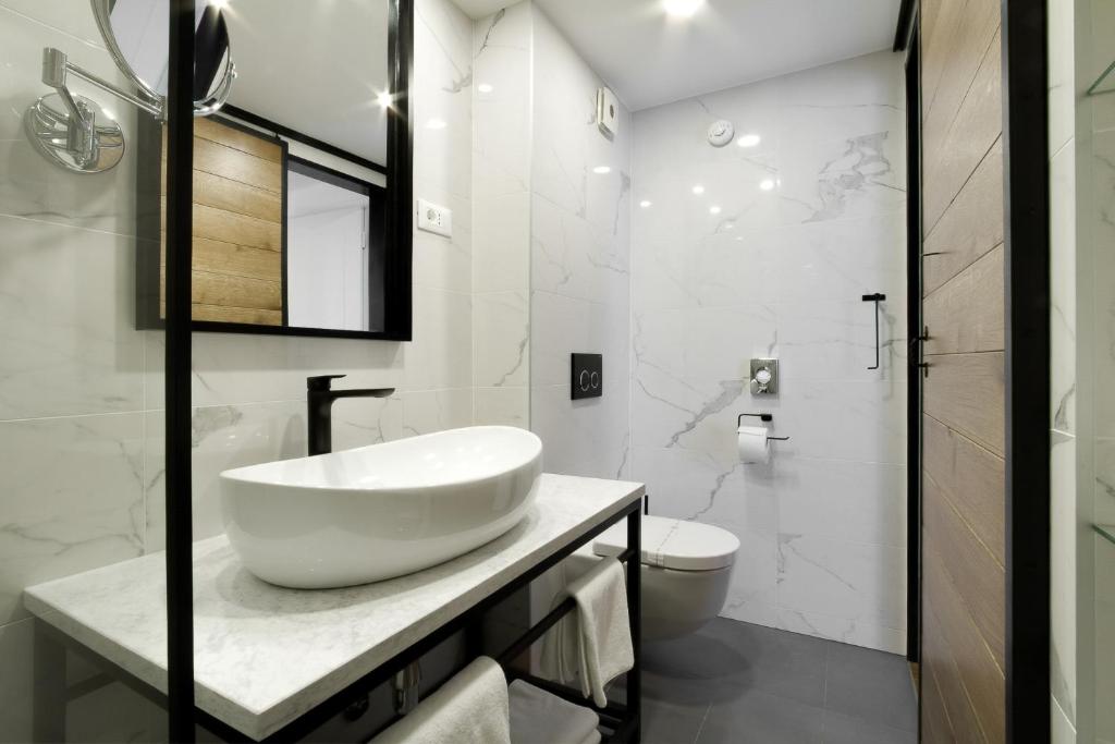 a white bathroom with a sink and a toilet at DeZign Superior Apartments & Rooms in Zadar