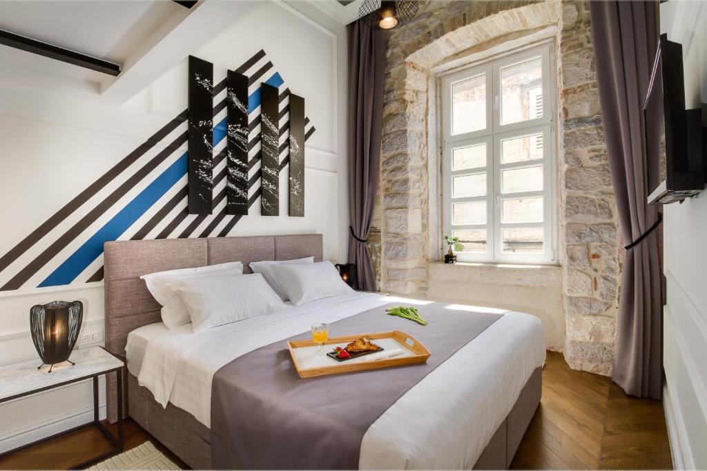 a bedroom with a large bed with a tray on it at DeZign Superior Apartments & Rooms in Zadar