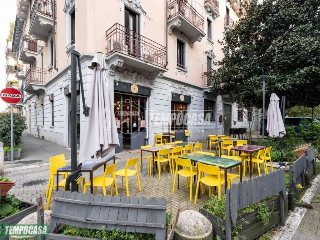 a restaurant with yellow chairs and tables and an umbrella at Governo Provvisorio House in Milan